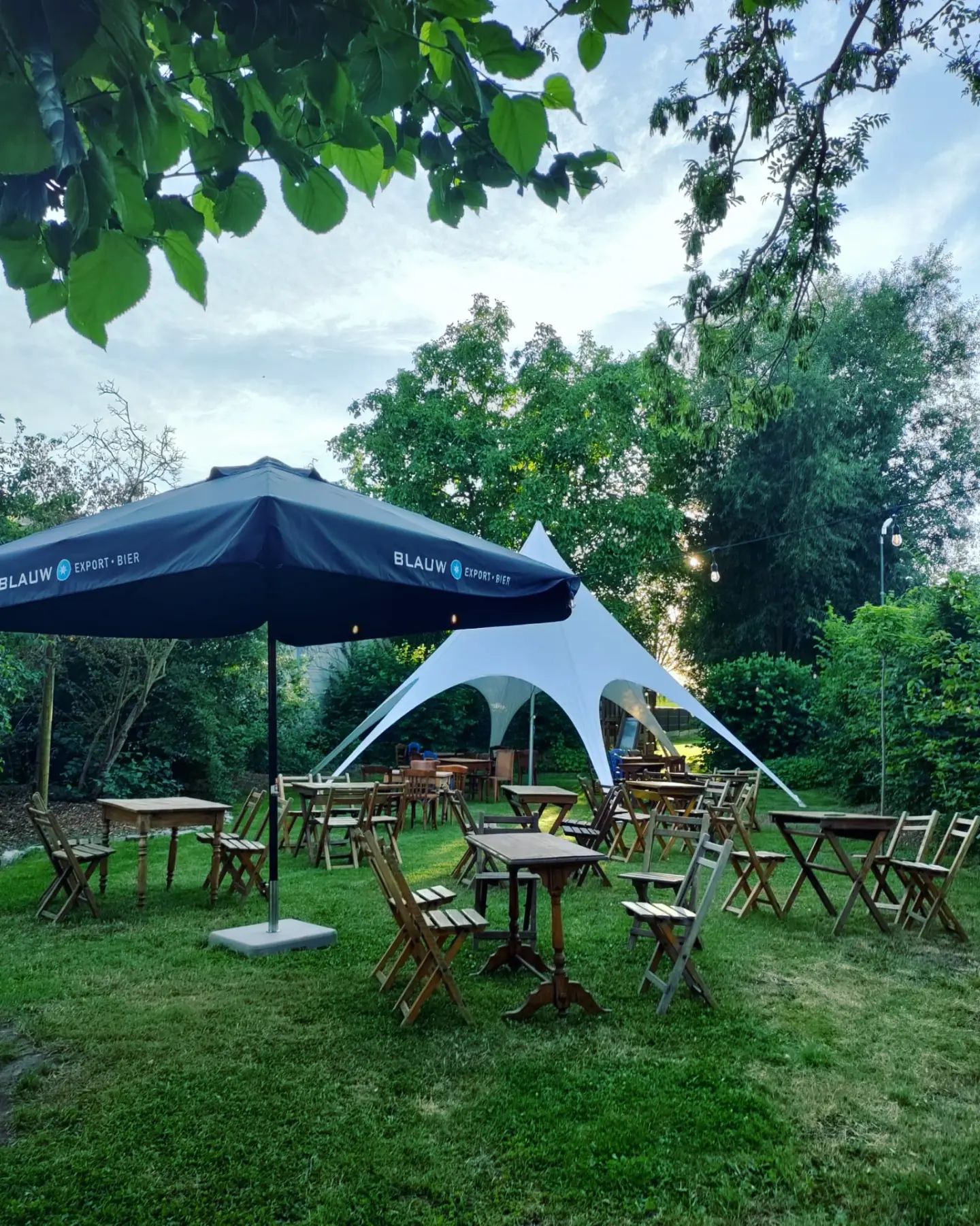 De tuin met stoeltjes en een grote tent.